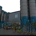Industrial Plant with Blue and White Silos Yellow Concrete Mixers and Surrounding Flowers