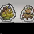 Two Colorful Cartoon Monster Figurines With Silver Speckled Bases Featuring MONSTER Text