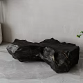 Black Irregular Shaped Sculpture Artistic Carving With Green Plants And Gray Background
