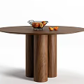 Round Wooden Dining Table With Three Legs And Metal Fruit Basket With Oranges