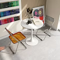 Round White Table with Two Orange Gray Transparent Chairs Metal Legs Interior with Vase Books