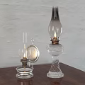 Two Vintage Glass Candle Lamps with Lit Wicks on Wooden Table Against White Wall
