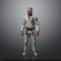 Man in White Judo Uniform with Black Belt Standing Against Gray Background