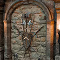 Stone Wall Arched Door Design With Metal Decorations And Wall Sconces