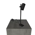 Black Modern Desk Lamp on Concrete Pedestal Against Textured Gray Wall