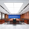 Wooden Paneled Conference Room With Rows of Tables Chairs Green Plants And Ceiling Lighting