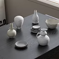 White Textured Ceramic Vessels Including Bowls Plates and Vases Arranged on Dark Wooden Table