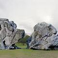 Unique Shaped Stone Garden Ornaments On Green Grassland With Blue Sky And Distant Hills