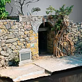 Natural Stone Wall With Arched Doorway And Wooden Tree Roots Decorative Elements