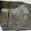 Ancient Archeological Site With Scattered Stones Excavated Earth And Grassy Edges
