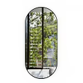 Large Oval Mirror Reflecting Green Trees And Buildings In Interior Space