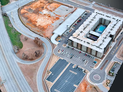 Aerial View of Modern Apartment Building with Parking Lot and Surrounding Roads Near Open Land 3d model
