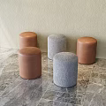 Five Round Brown and Gray Stools on Marble Floor Against Light Wall