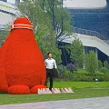 Giant Red Plant Shaped Garden Ornament with People Taking Photos in Outdoor Park