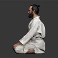 Man In White Judo Uniform Sitting Cross Legged On Dark Background With Beard