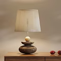 Wooden Base Table Lamp With Beige Lampshade And Two Red Fruits On Wooden Table