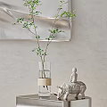 Transparent Vase With Green Branches Beige Band Near White Elephant Figurine Against Light Colored Wall