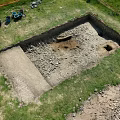 Top Down Aerial View Of Outdoor Archaeological Excavation Trench On Grassy Site With Working Tools