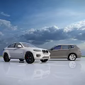 Two White And Silver Cars Parked In Open Field With Blue Sky And Clouds