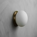 Minimalist White Globe Wall Lamp With Brass Base On Gray Textured Wall