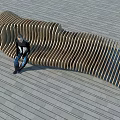 Wooden Curved Slatted Outdoor Chair In Modern Outdoor Setting With Stone Floor