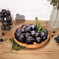Black Fruits on Wooden Plate with Green Leaves Scattered Small Fruits Near Transparent Vase