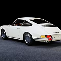 White Classic Porsche Sports Car With Red Interior Parked On Gray Floor Against Black Background