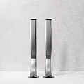 Two Modern Silver Tower Speakers Against Grey Wall On White Countertop
