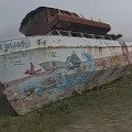 Abandoned Boat With Rusted Hull Grassy Field And Shark Graffiti Artwork
