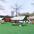 Scenic Urban Park Landscape With Green Grass Tents Ice Cream Trucks And Tall Buildings