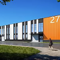 Modern Industrial Warehouse With Orange And White Exterior Large Windows Number 27 And Surrounding Green Lawn