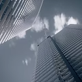 Airliner Flying Between Two Modern Skyscrapers In Sky With Clouds