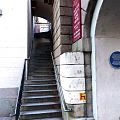 Stone Stairs With Handrail Near Archway And Red Sign Blue Plaque On Building Exterior