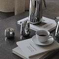 Elegant Stainless Steel Tea Set With White Cup Saucer And Magazines On Gray Table