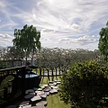 Lush Green Garden Landscape With White Building And Trees Under Blue Sky With Clouds