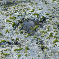 Weathered Rocky Terrain Covered With Green Moss And Small Puddle In Center