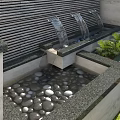 Modern Garden Feature With Water Flow Stone Border Pebbles Green Plants And Striped Wall