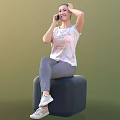 Woman Sitting On Black Cube Talking On Phone In White T-shirt Gray Pants White Sneakers