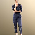 Woman in navy blue jumpsuit with long sleeves and pockets standing against neutral background