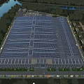 Modern Industrial Factory With Solar Panels on Roof and Green Surroundings Near River