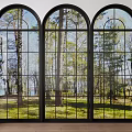Black Framed Arched Floor To Ceiling Windows Reveal Trees Grass And Side Potted Plants