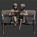 Two Young Men Sitting On Wooden Bench Reading Book Together In Bronze Sculpture