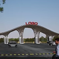 Modern Arched Entrance Gate With LOGO Sign Vehicles Passing By And Green Trees Around