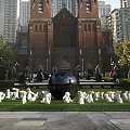 Outdoor Landscape Sculptures With Black Sphere And White Rabbits On Lawn Near Red Brick Building