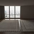 Two Patterned Square Rugs with Different Colors in Room with Wooden Floor and Large Windows
