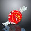 Lindt Lindo Red Candy With White Leaf Pattern On Crinkled Wrapper Against Black Background
