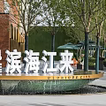 Illuminated Circular Water Fountain With Surrounding Trees And Paved Plaza Ground
