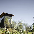 Black Wooden Guesthouse Building Exterior With Large Windows And Hillside Greenery