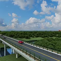 Modern Highway Bridge over River with Green Forest Blue Sky White Clouds and Moving Vehicles