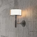Modern Wall Sconce With White Striped Lampshade Emitting Warm Light On Textured Wall